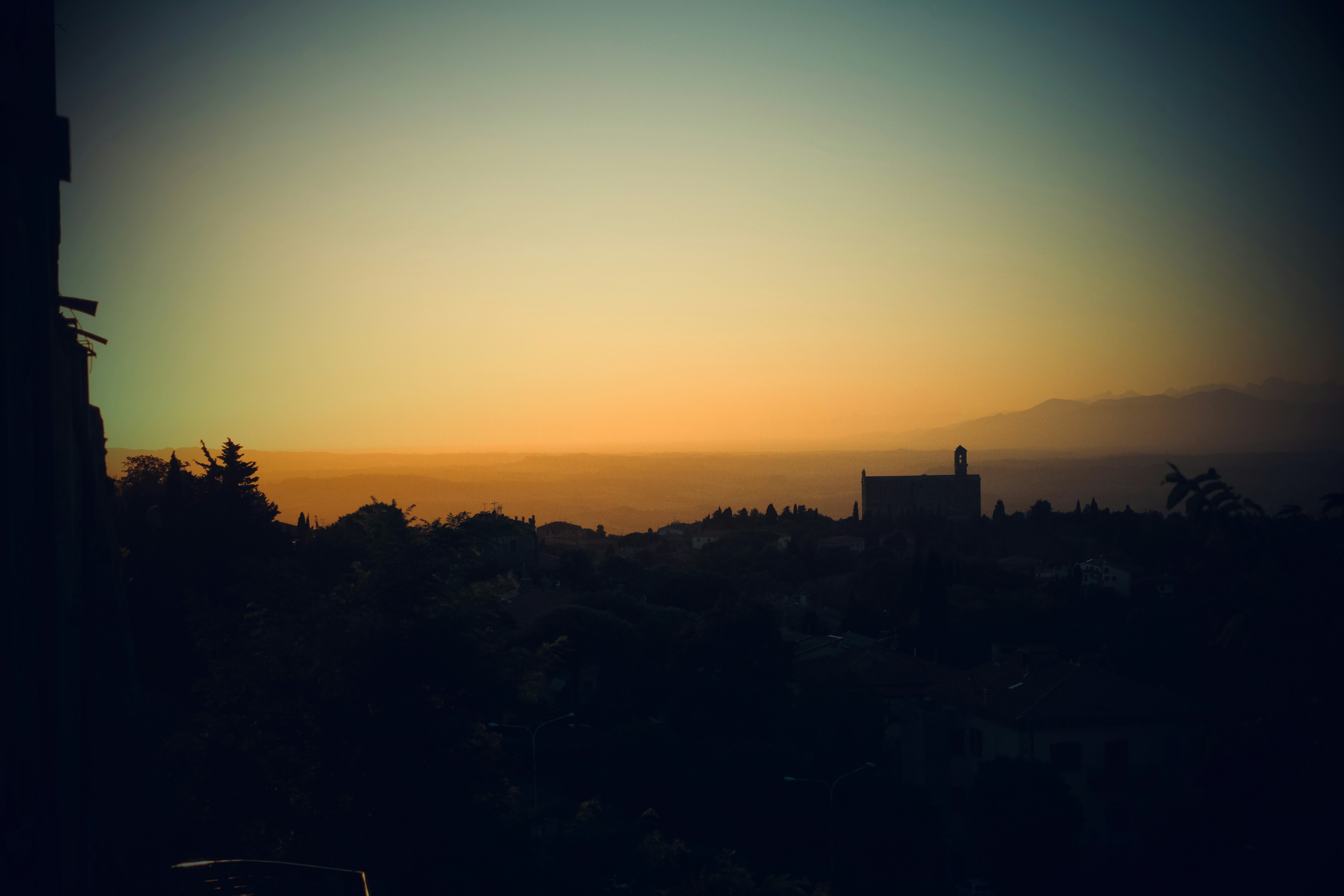 The sun is setting over a city and hills