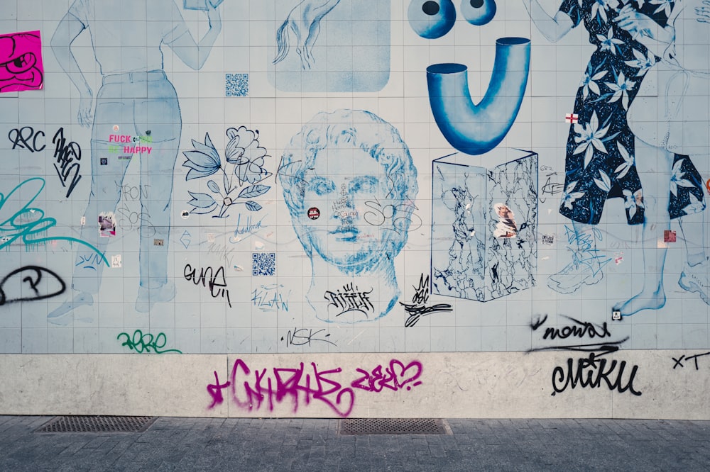 a wall covered in lots of graffiti next to a sidewalk