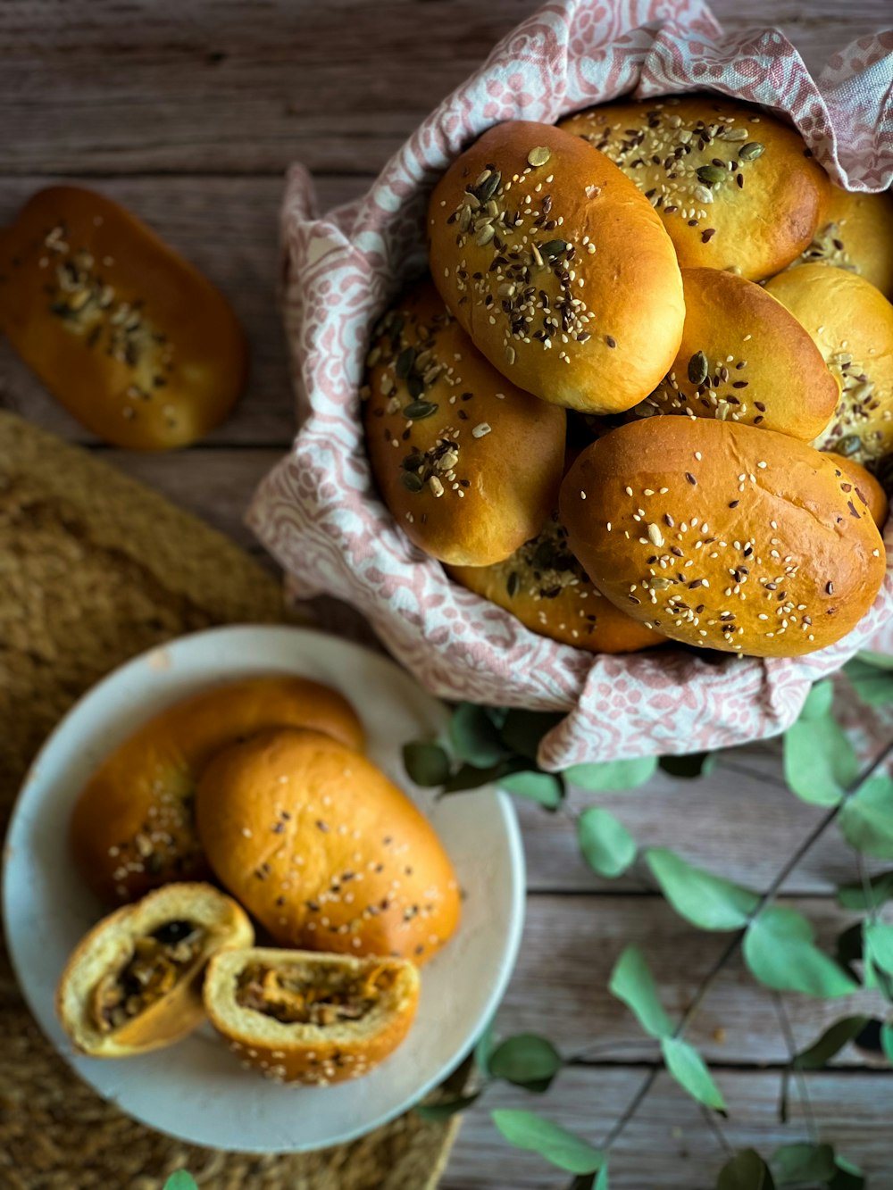 a bowl of sesame seed buns next to a plate of sesame seed buns