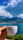 Close-up of a woman enjoying a cup of premium coffee while wearing a brisaviva t-shirt near the ocean.