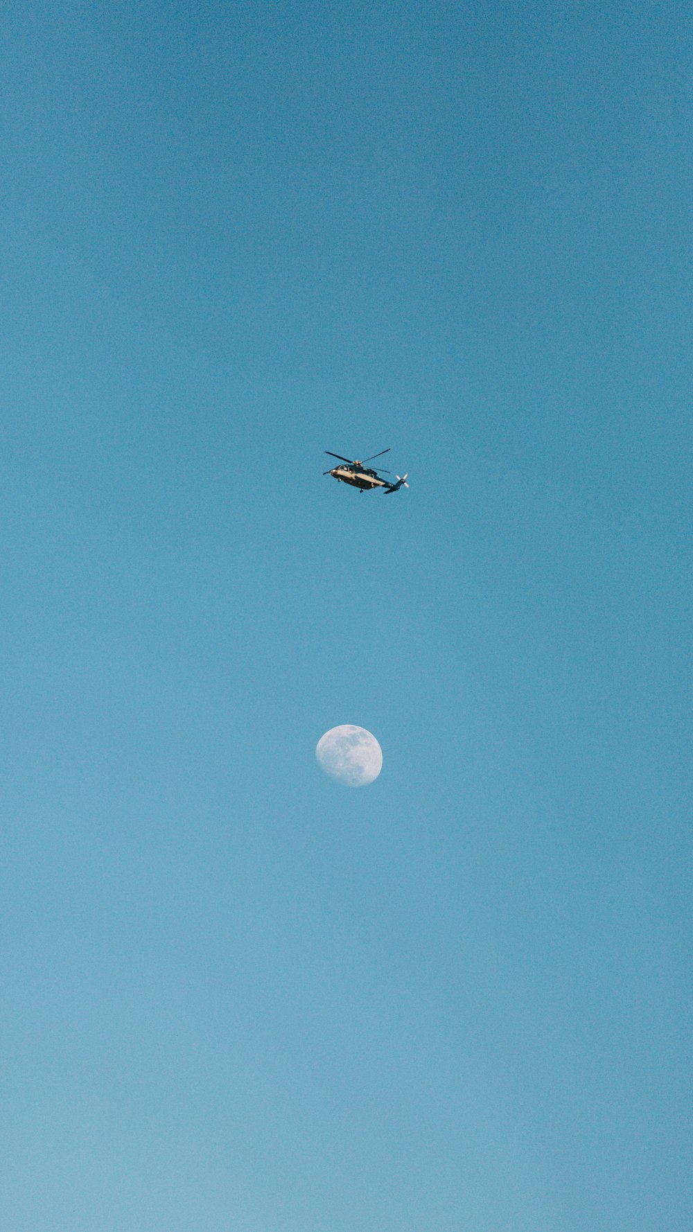 a helicopter flying over the moon in a clear blue sky