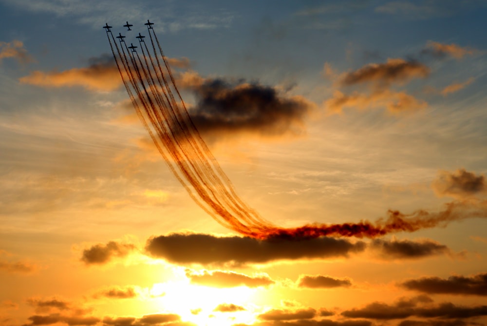 a plane flying in the sky at sunset