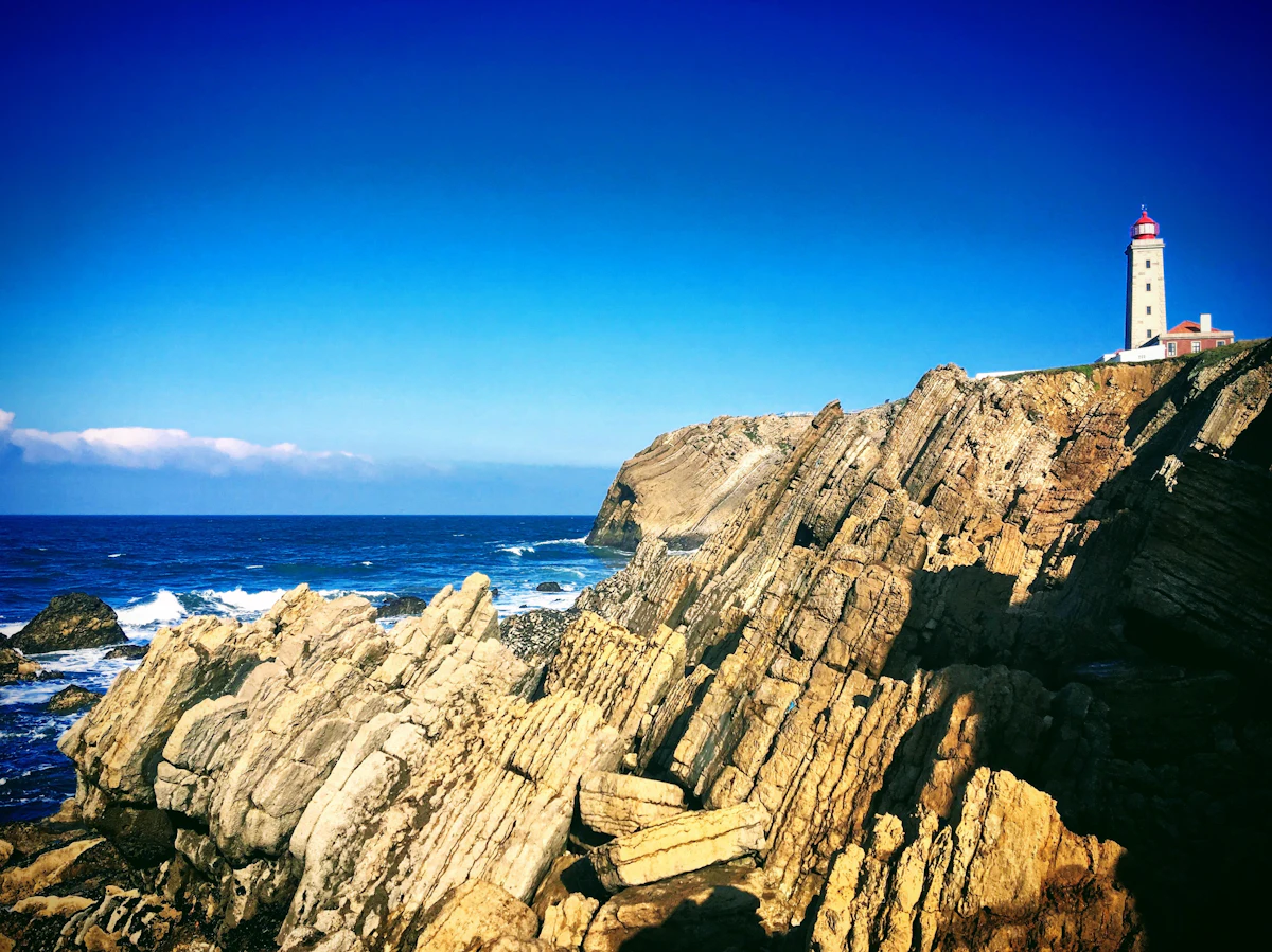 A lighthouse on a rocky headland above the sea