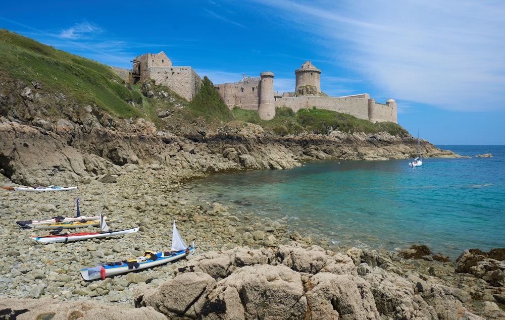 Una spiaggia rocciosa con un castello sullo sfondo