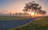 A serene landscape with a sunrise illuminating a path through a forest, symbolizing new beginnings and personal growth.