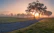 A serene landscape with a sunrise illuminating a path through a forest, symbolizing new beginnings and personal growth.