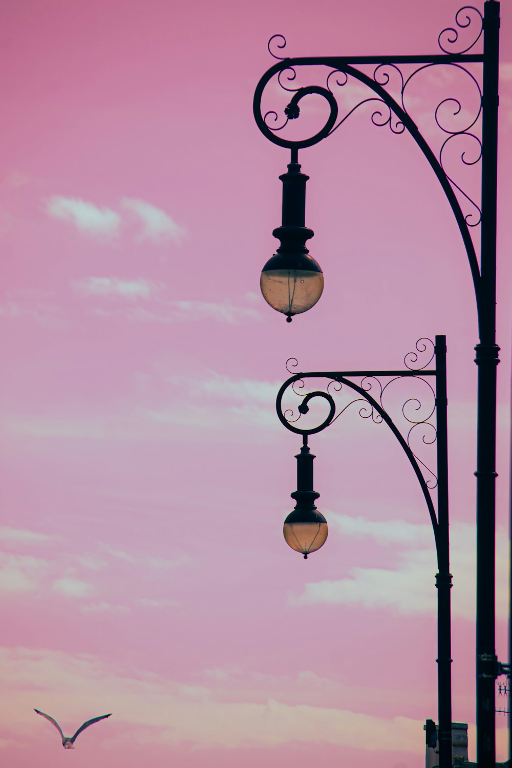 a street light with a pink sky in the background