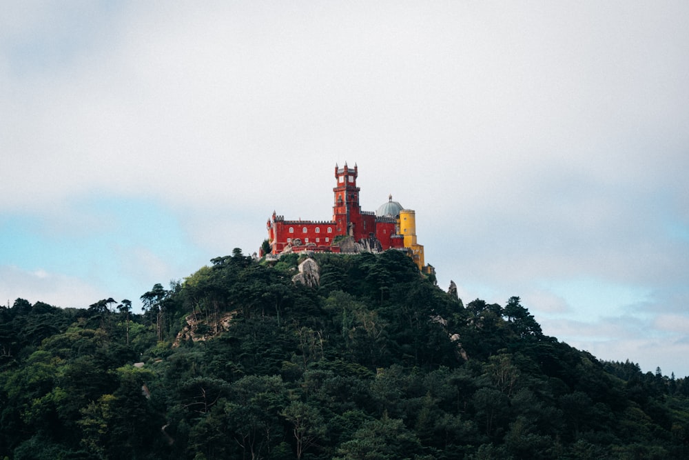 a large red building on top of a lush green hillside