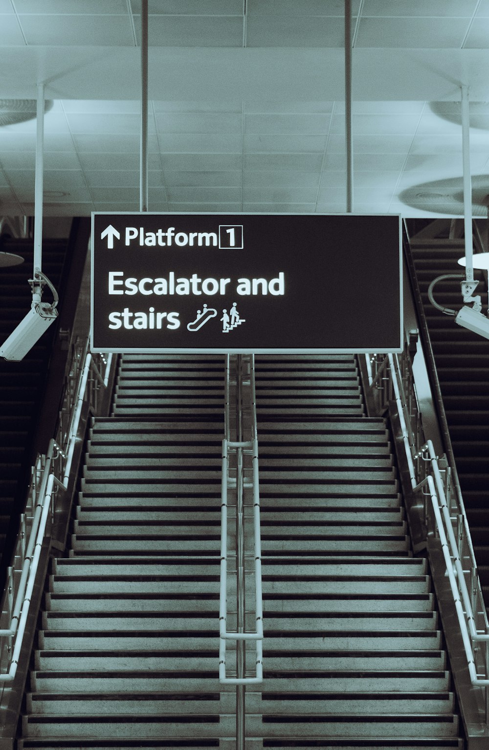 an escalator and stairs sign at an airport