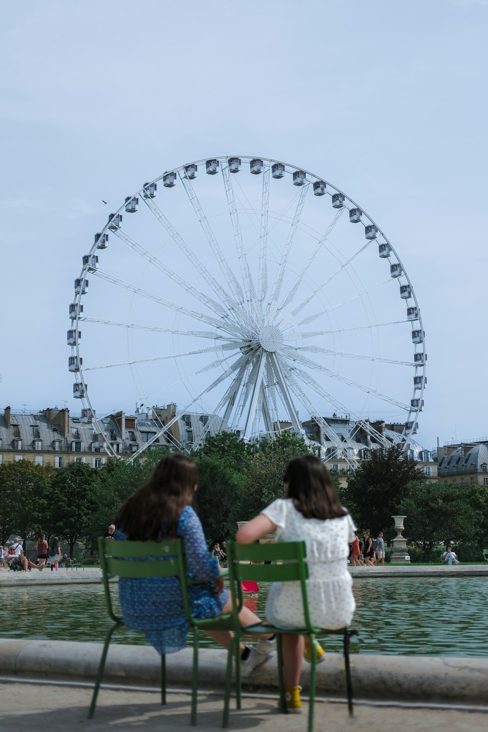 two little girls sitting in chairs in front of a ferris wheel