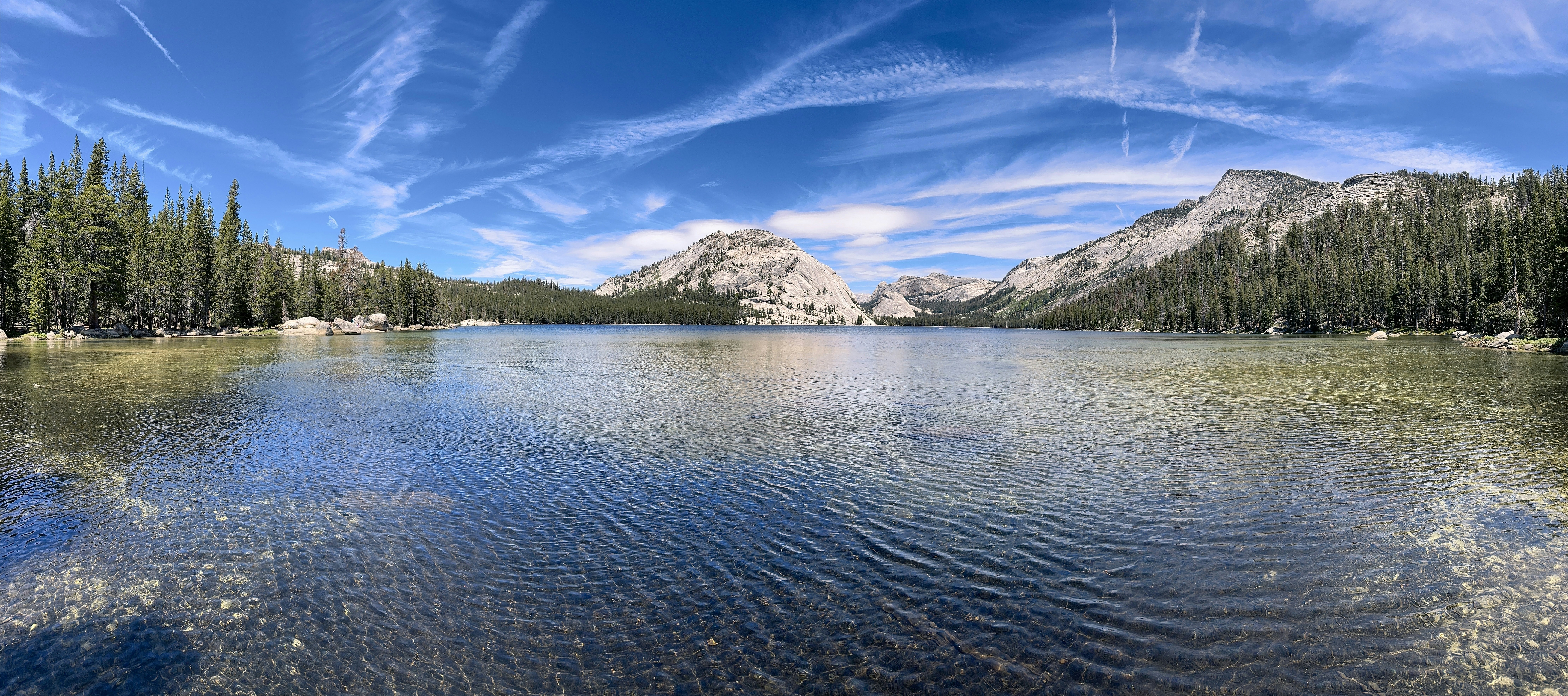 um lago cercado por árvores e montanhas sob um céu azul