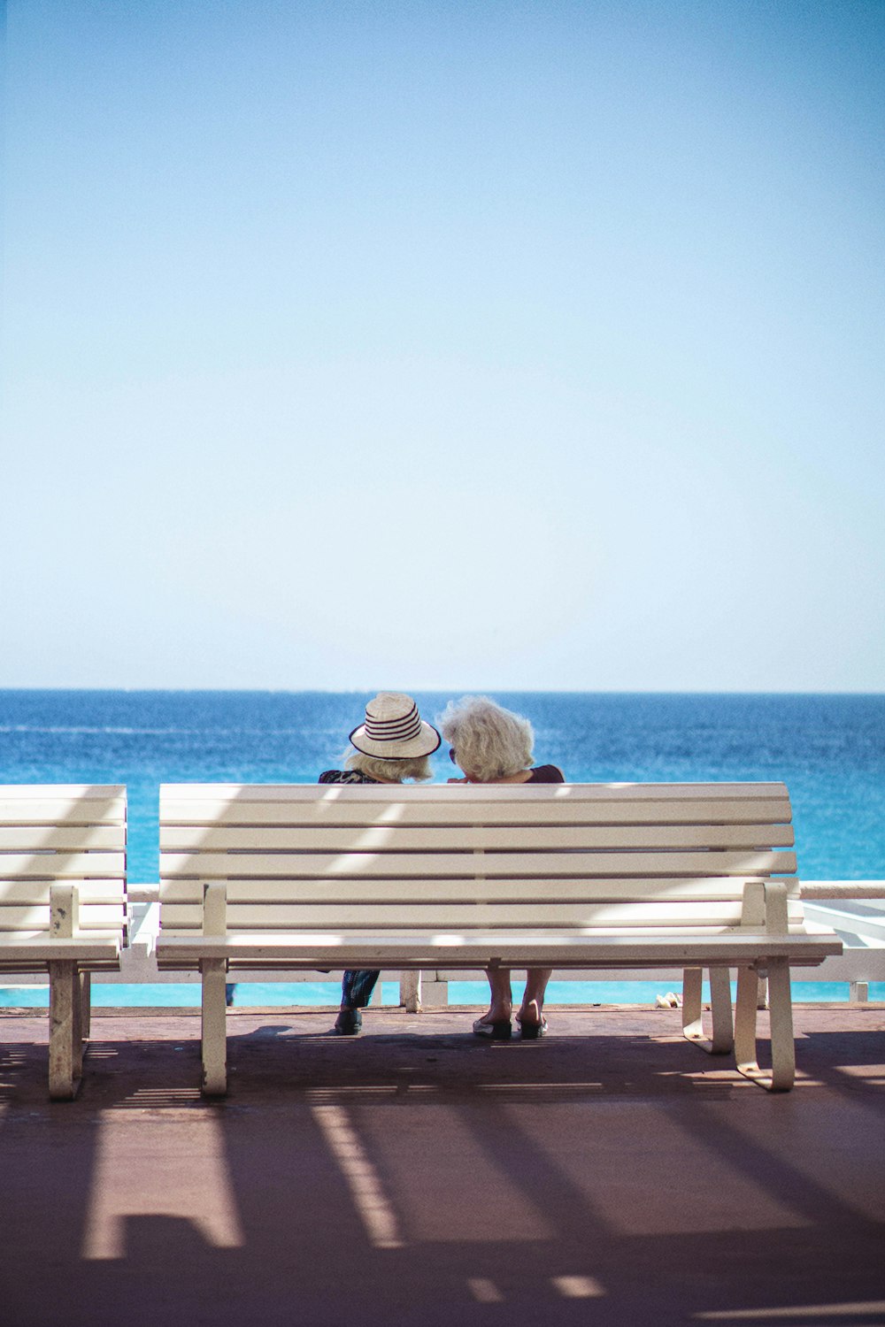 ベンチに座って海を眺める二人
