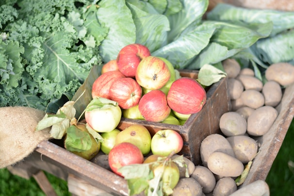 A vibrant crate overflowing with freshly picked fruits resting on a rustic wooden table.