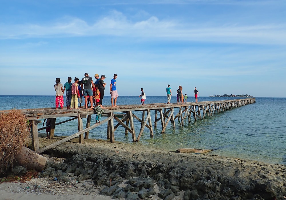 a group of people standing on a wooden pier
