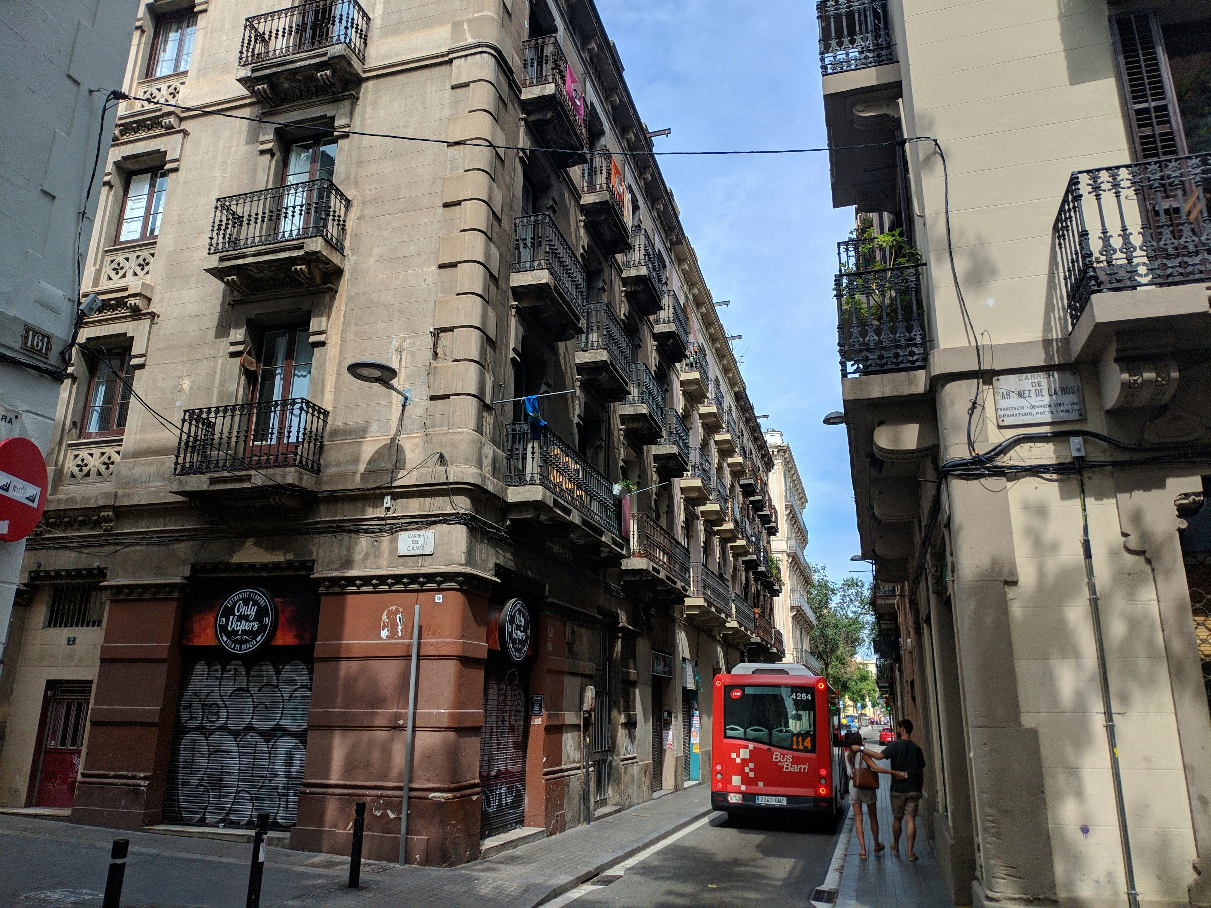 a red bus driving down a street next to tall buildings