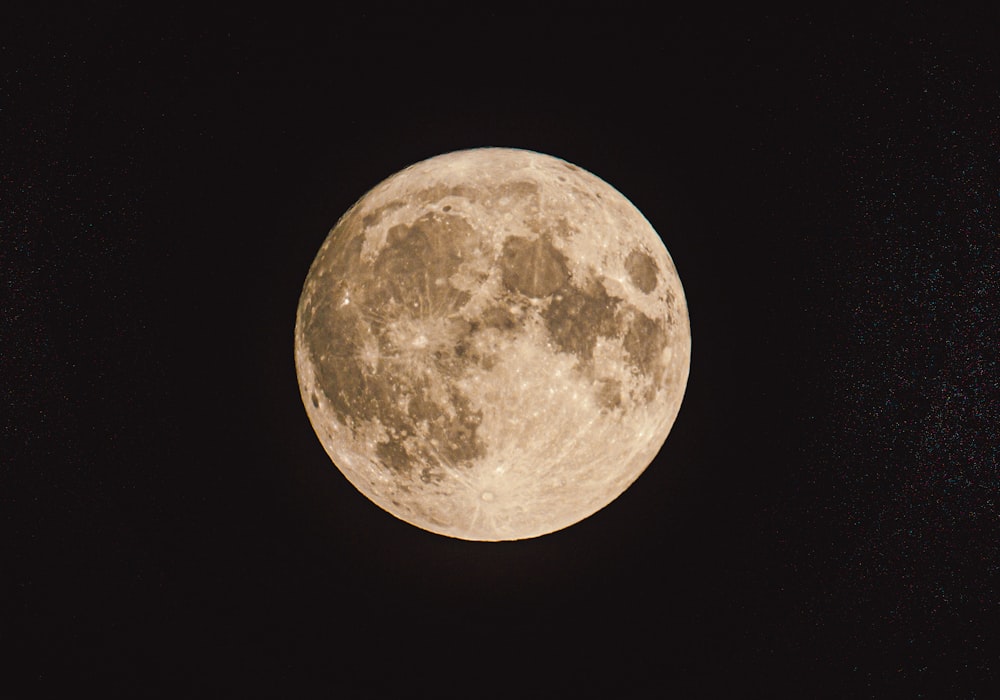 a full moon is seen in the dark sky