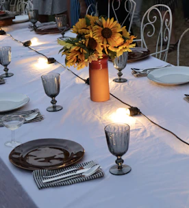 A beautifully set long table outdoors with guests enjoying a feast under string lights.