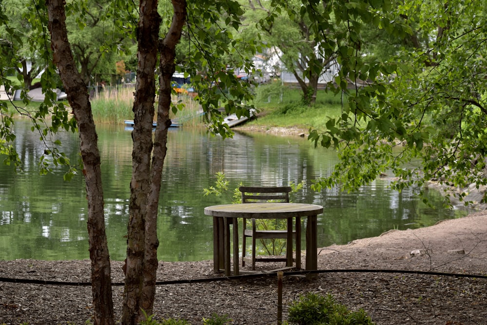 a wooden table and chair sitting next to a body of water