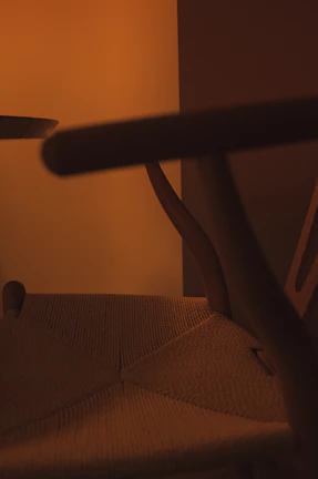 Close-up of an intricately carved teakwood royal chair with golden accents under soft cinematic lighting.