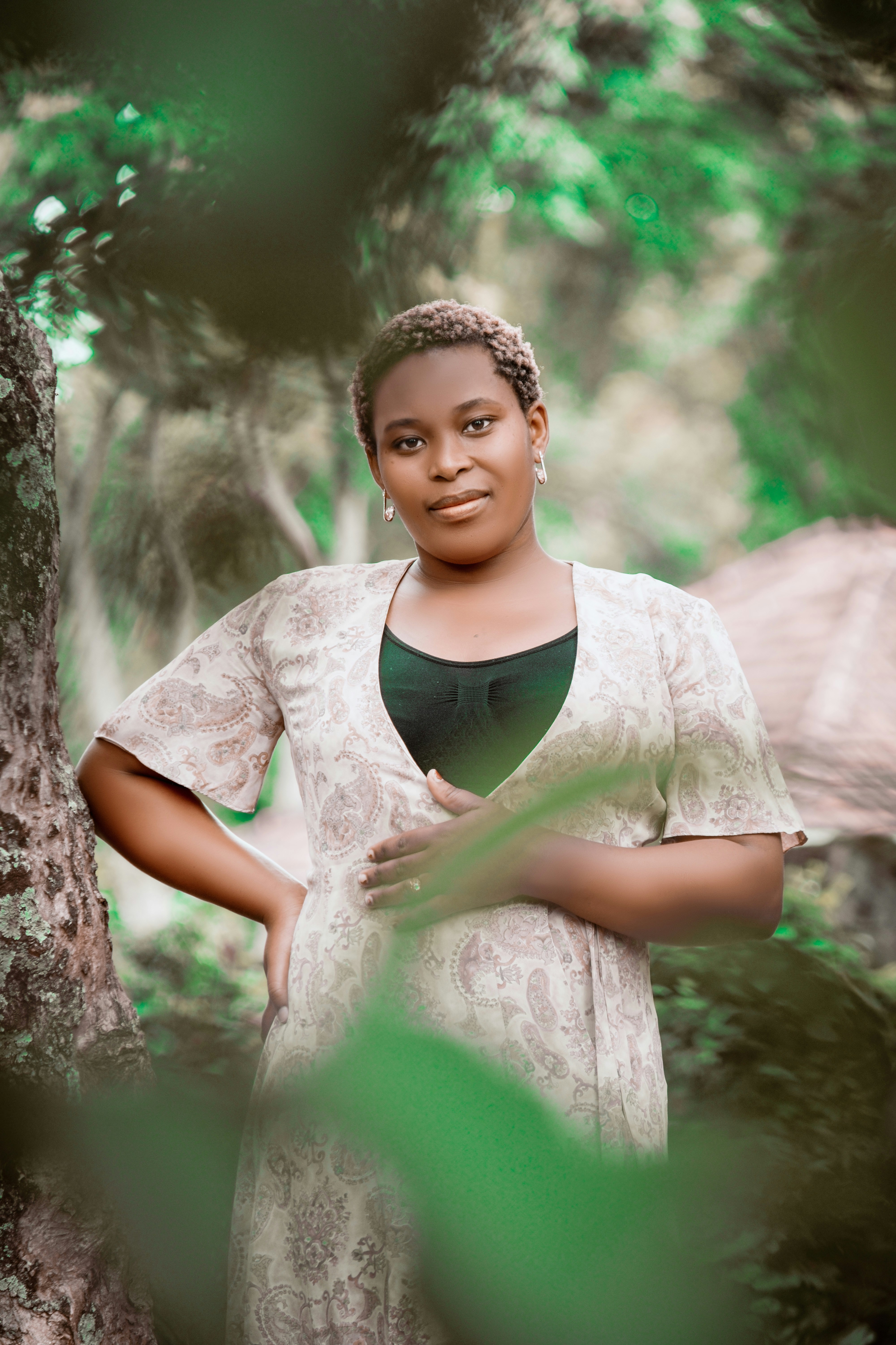 Portrait of a Black woman in her thirties outdoors, natural light, calm and confident expression, green background