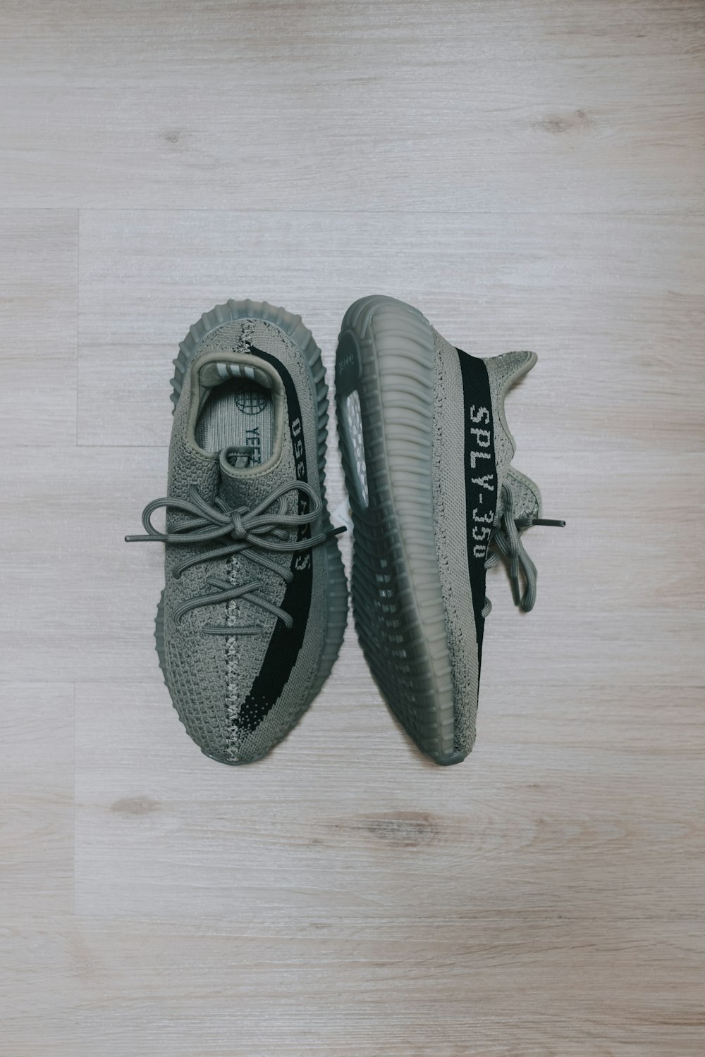 a pair of grey sneakers sitting on top of a wooden floor
