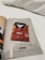 A magazine page features a red soccer jersey with yellow and dark blue accents, encased in a transparent plastic bag. The jersey is branded with 'adidas' and has a badge resembling the Spanish national team's emblem on the chest. The page is numbered 289 and includes some text references and credits at the bottom.