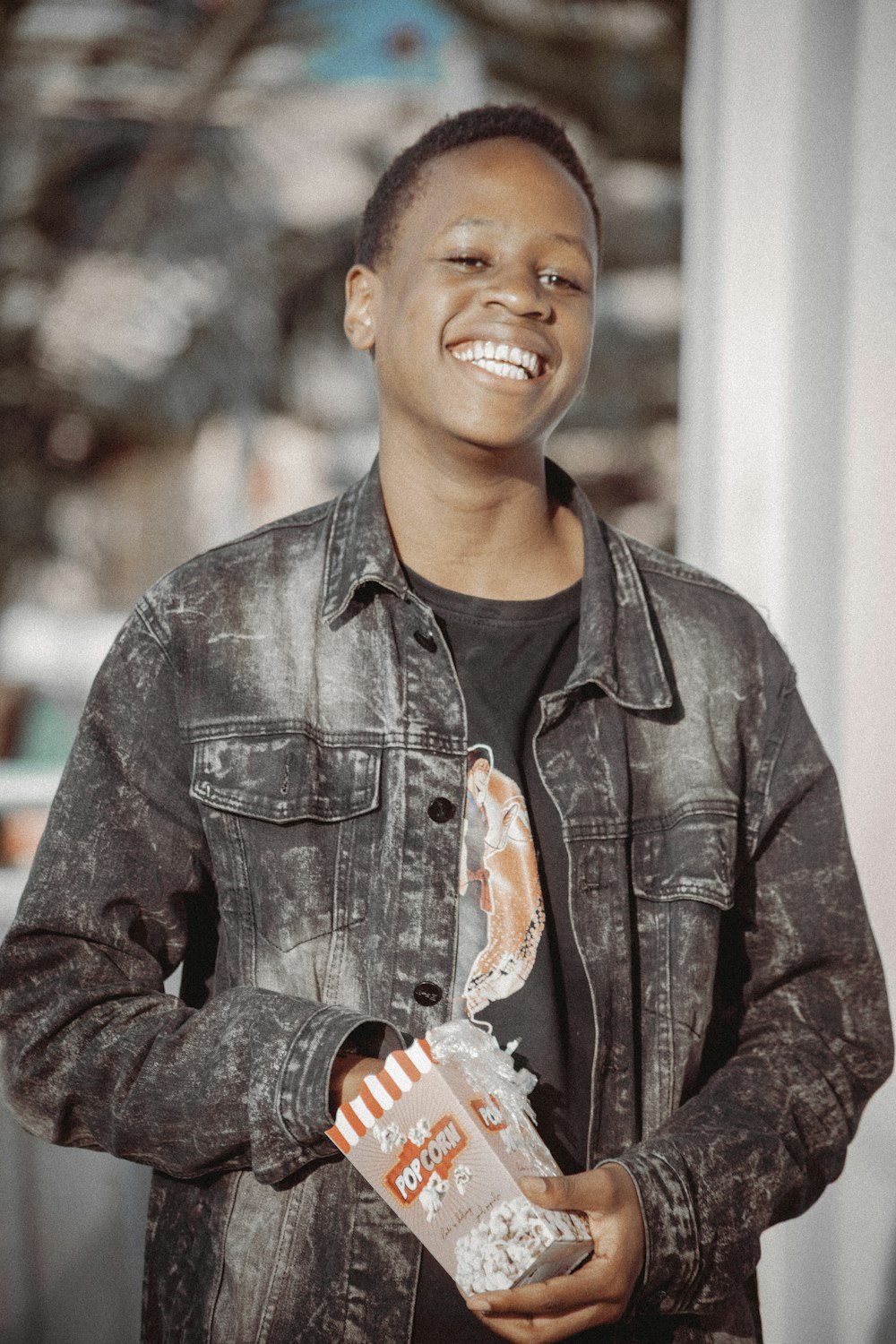 a man holding a box of popcorn and smiling