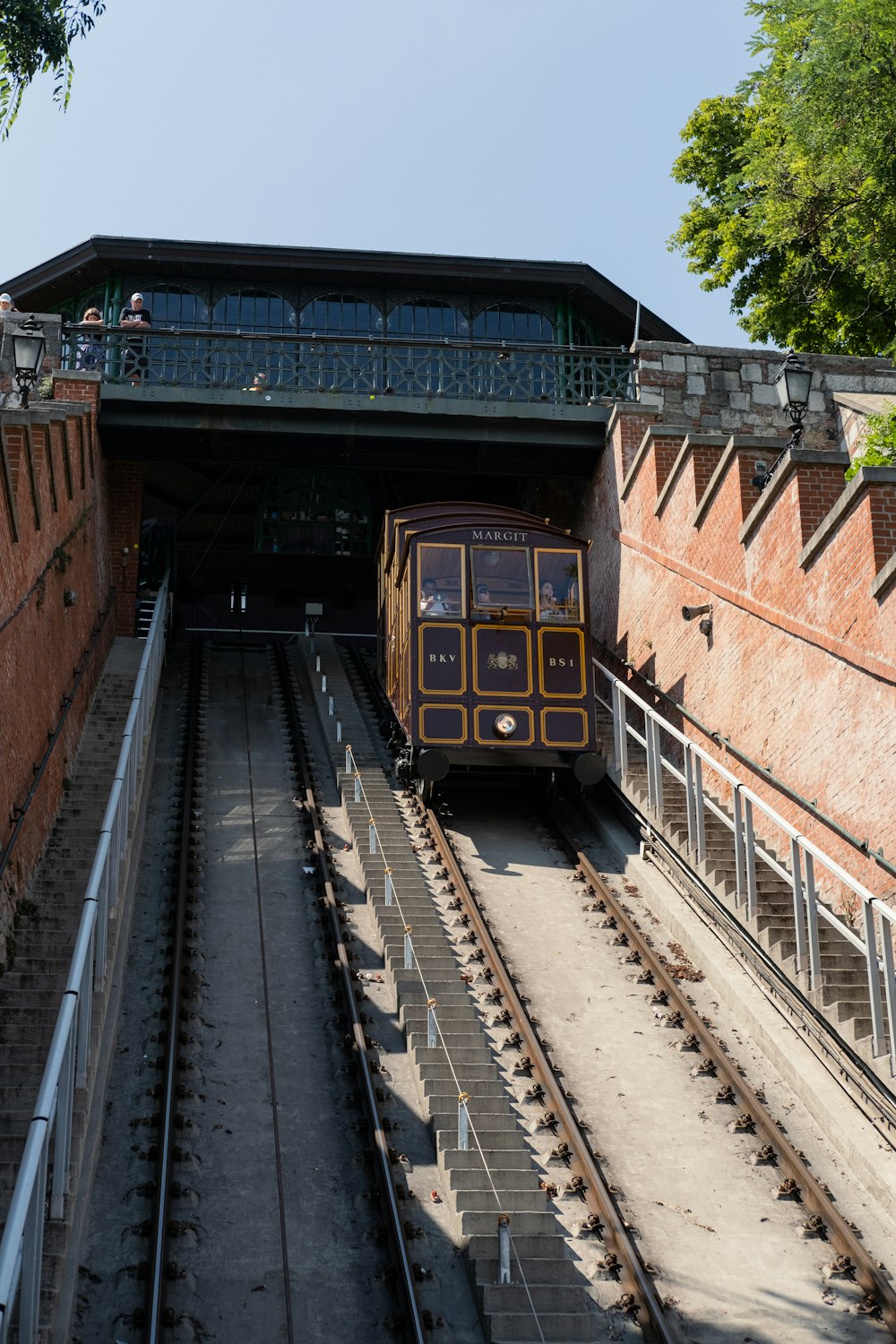 a train coming out of a tunnel under a bridge