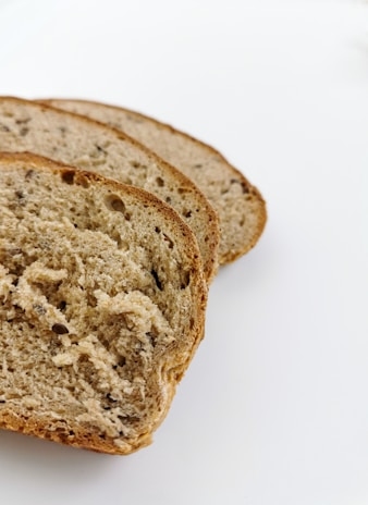 Organic grains and seeds arranged beside a loaf, emphasizing ingredient quality.