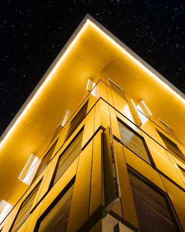 The sleek, modern Foss Group headquarters building in Yerevan, Armenia, glowing under a deep black sky with subtle gold accents.