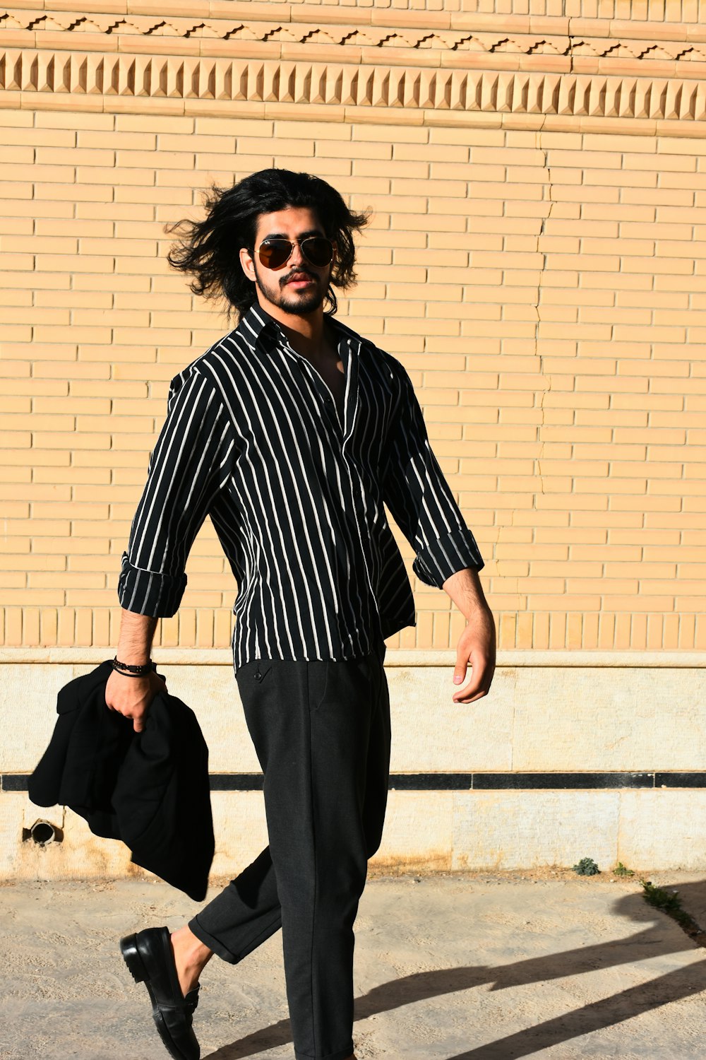 a man with long hair and sunglasses walking down the street