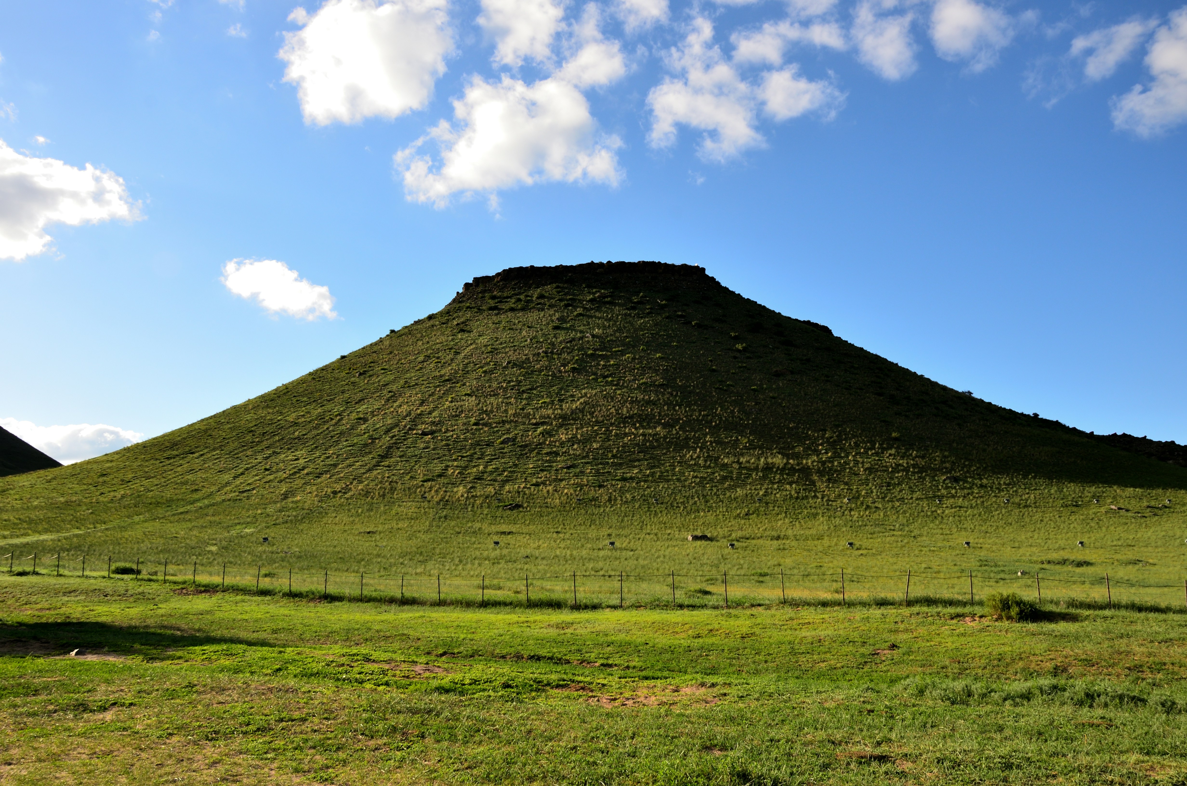 a large grassy hill with a sky background