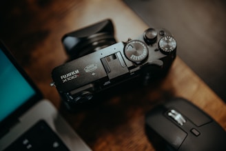 Close-up of a Sony a7 IV camera with a prime lens resting on a wooden desk beside photography accessories.