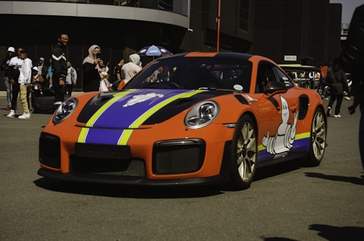 A colorful car wrapped with bold branding graphics parked outside a small business.