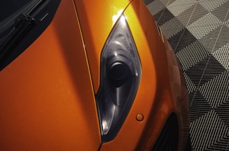 Close-up of a sleek car hood reflecting neon lights in deep blues and pinks at an Orlando event.