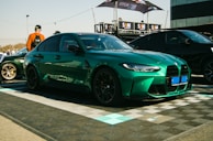 A vibrant green sedan known for excellent gas mileage parked near the dealership entrance.