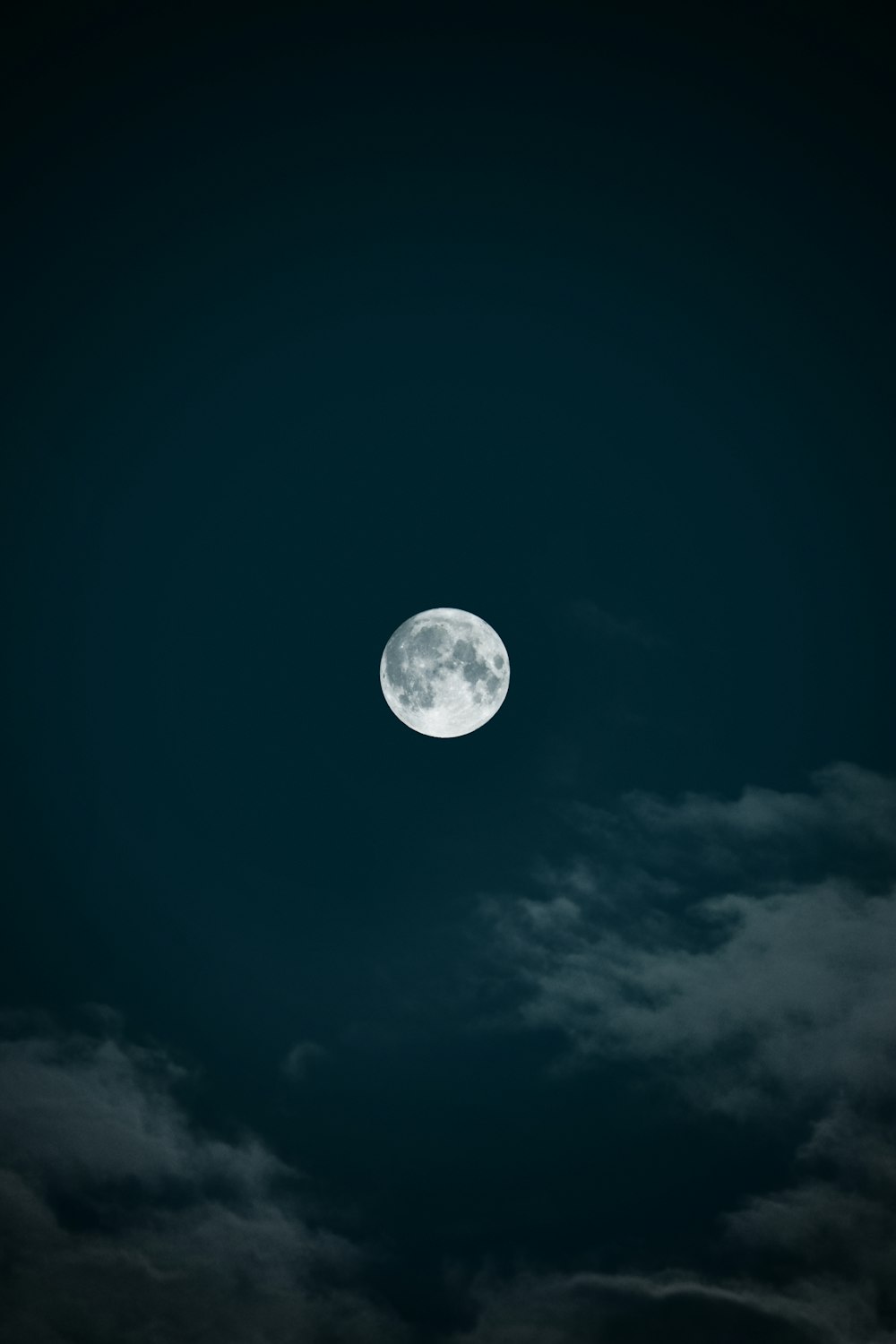 a full moon in a dark sky with clouds