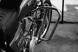 A close-up view of a motorcycle, focusing on the engine and part of the frame. The bike features chrome details, a seat with a stitched pattern, and visible branding on the fuel tank.