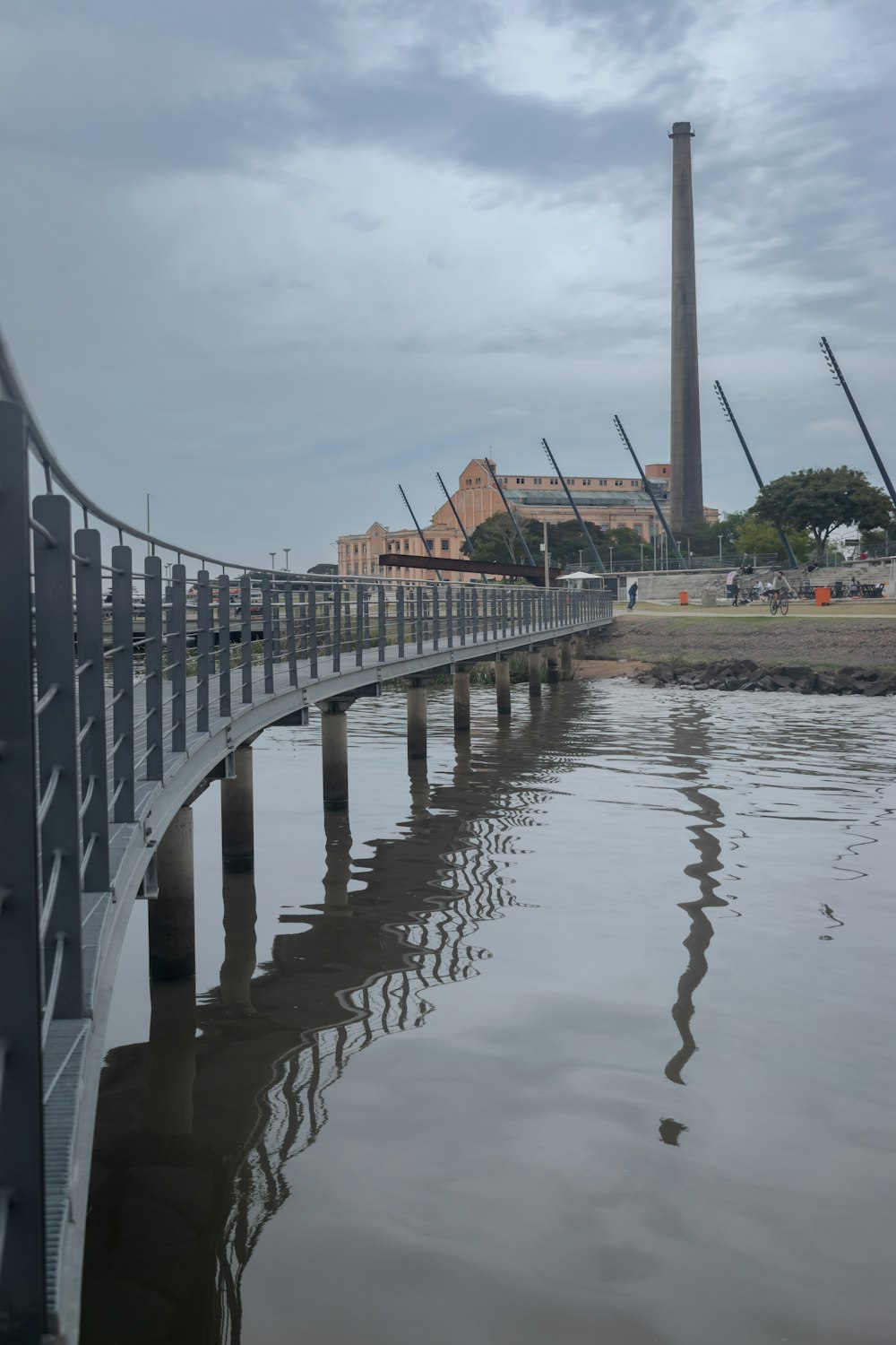 a bridge over a body of water with a factory in the background