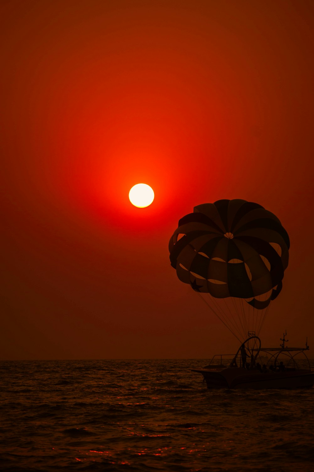 Ein Heißluftballon, der bei Sonnenuntergang über den Ozean fliegt