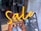 Bright neon signage spells out the word 'Sale', suspended in front of a shop window. The interior shows pairs of shoes displayed on an orange, tiered rack.
