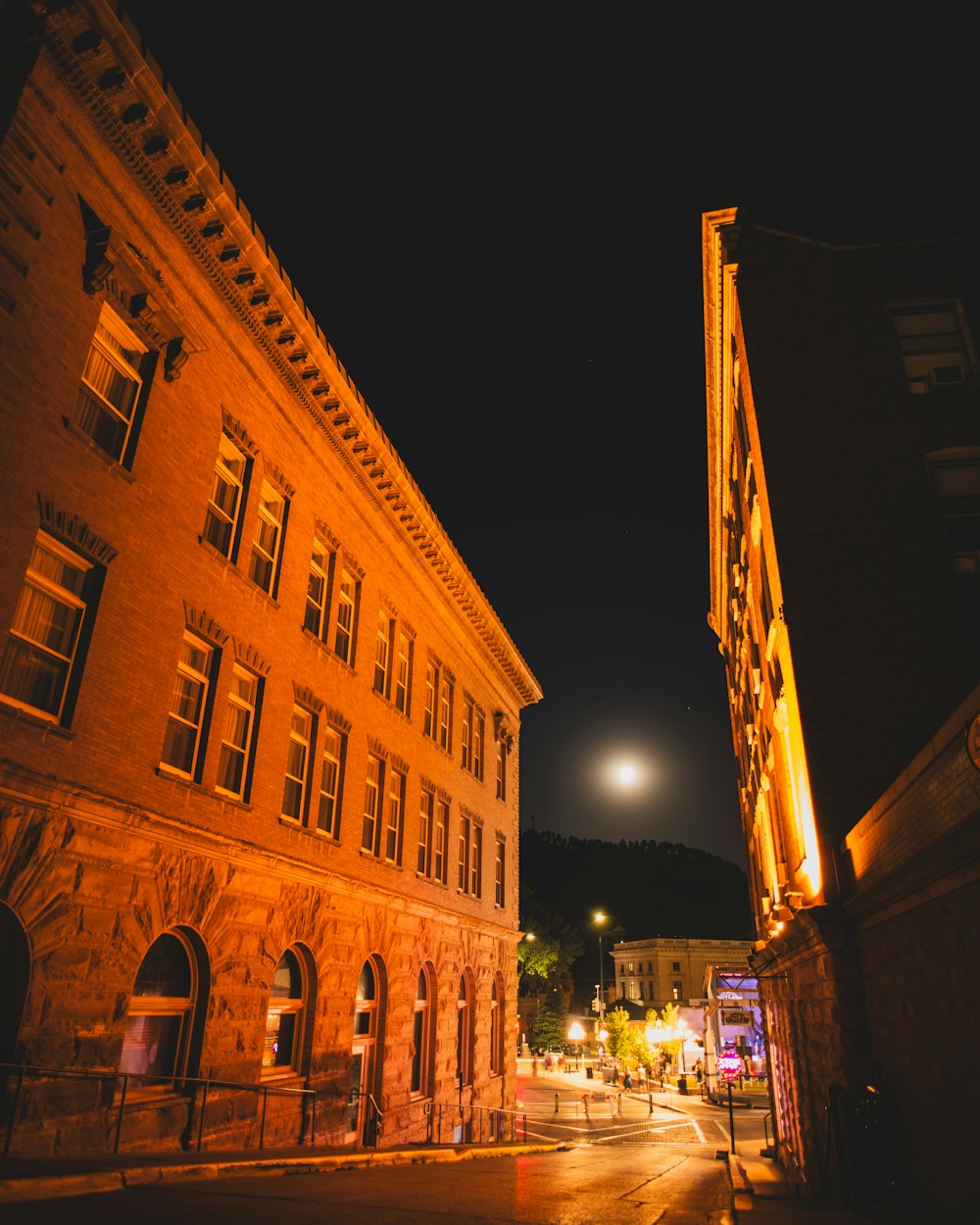 a city street at night with a full moon in the sky