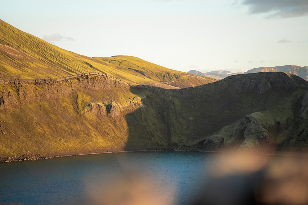 a lake surrounded by mountains with a bird flying over it