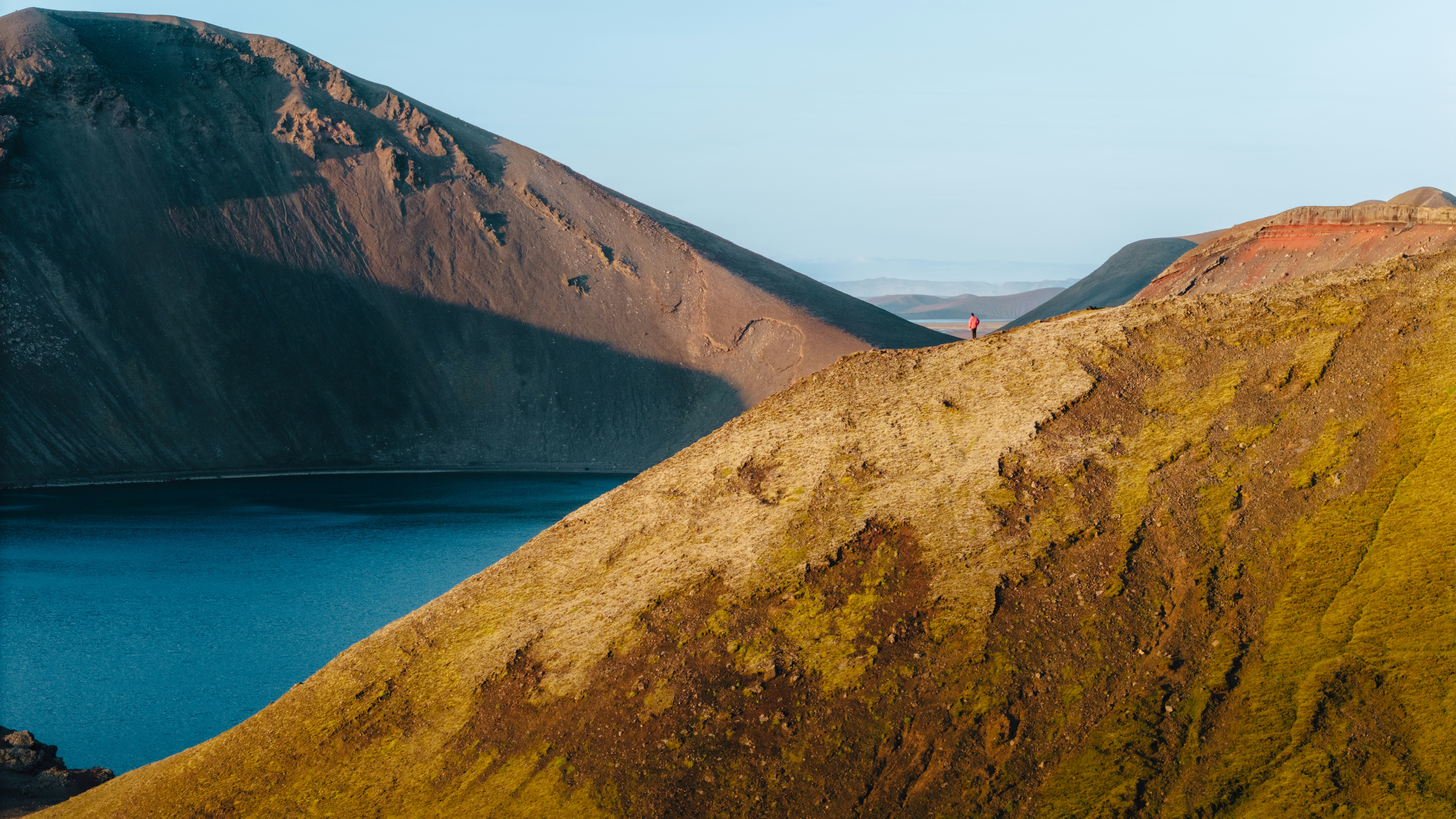 a person standing on top of a mountain next to a body of water, Feeling small looking down on the vast scale of the Iceland Highlands
