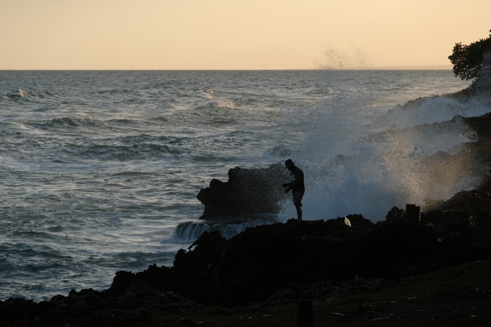 a person standing on a rock near the ocean