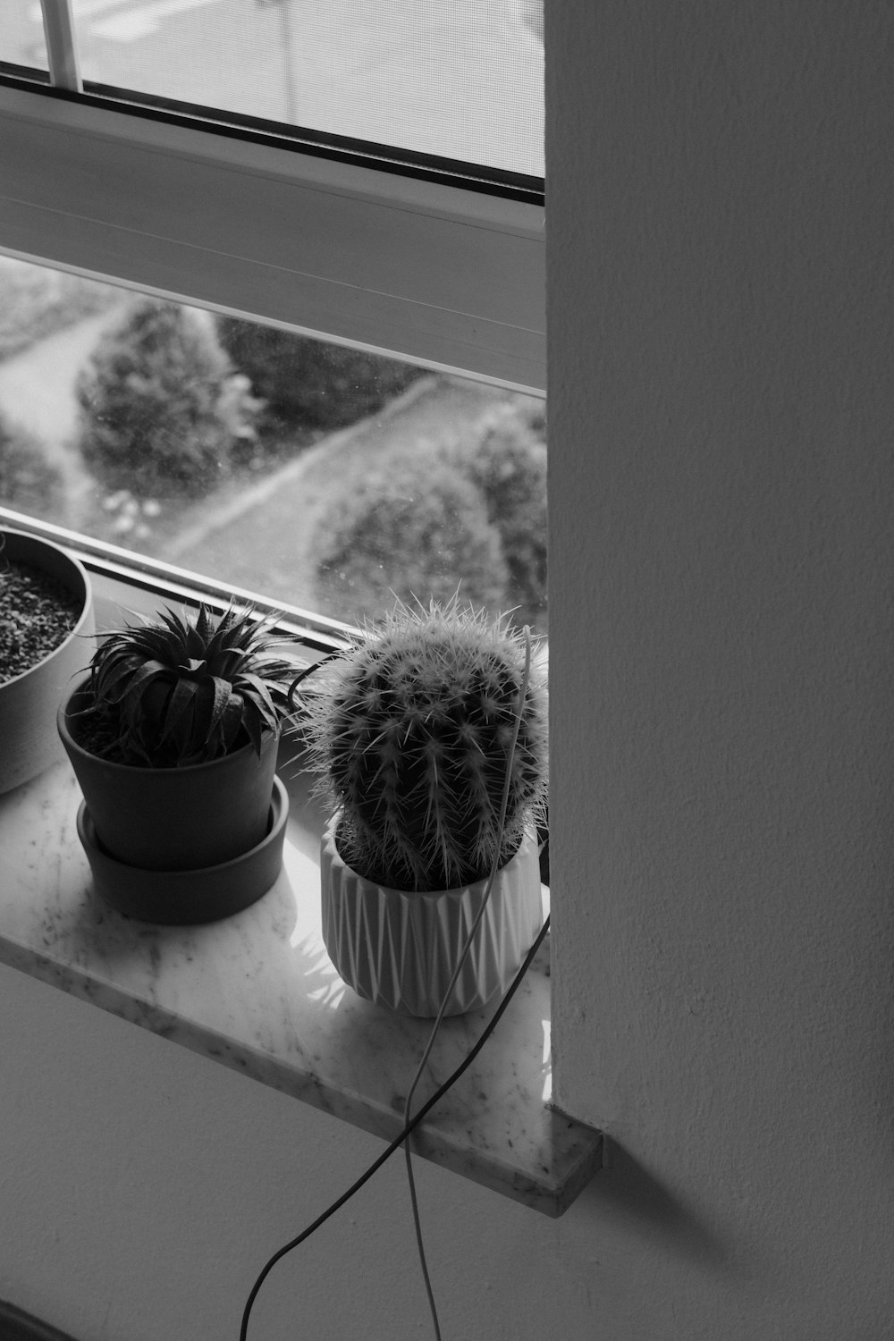 a window sill with three potted plants on it