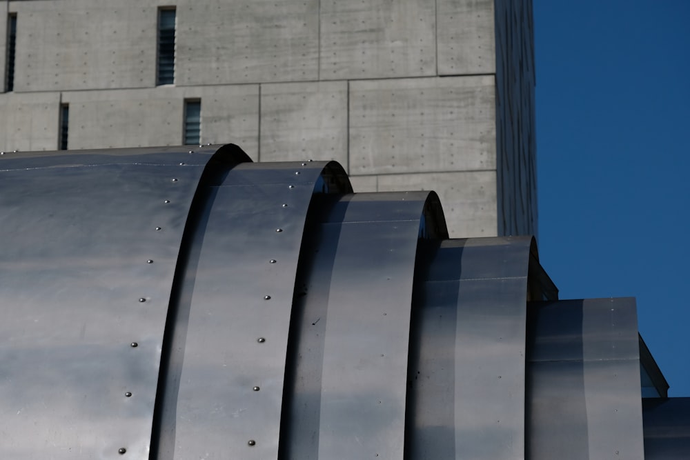 a close up of a metal structure with a building in the background