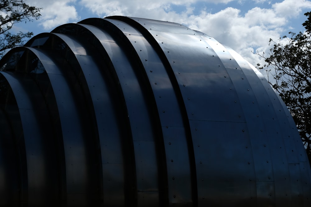 a large metal structure sitting next to a forest