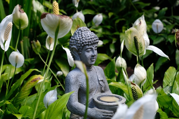 a buddha statue sitting in a field of flowers