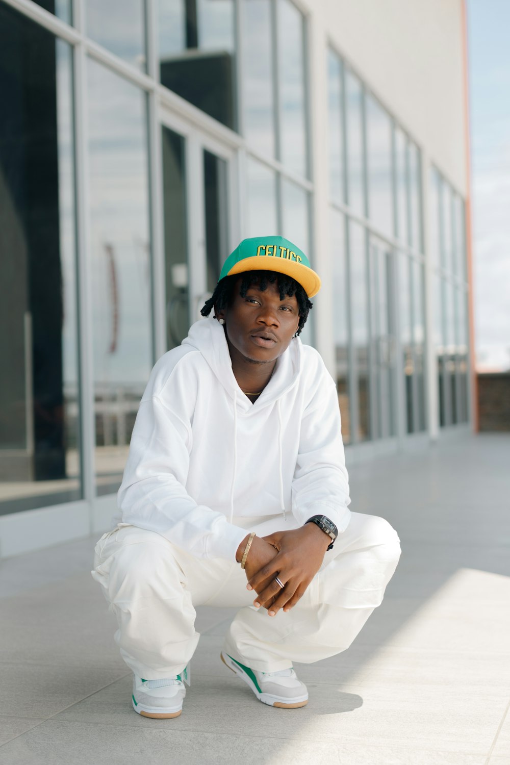 a man in a green and yellow hat squatting on the ground